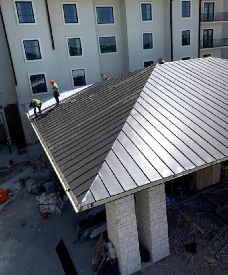 Crew installing standing seam metal roof panels on a commercial project in Bellaire